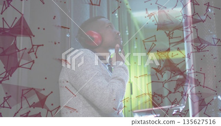 Touching chin engineer wearing gray sweater and red headphones in foam studio with green LED strip Touching chin engineer wearing gray sweater and red headphones in foam studio with green LED strip 135627516