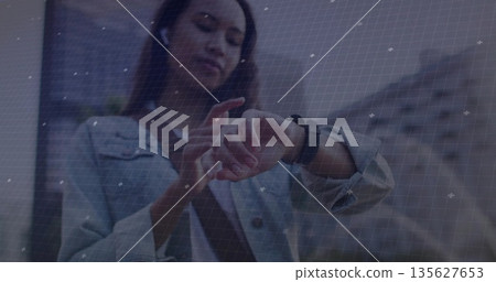 Woman in denim jacket and crossbody bag tapping smartwatch on city sidewalk, with wireless earbuds Woman in denim jacket and crossbody bag tapping smartwatch on city sidewalk, with wireless earbuds 135627653