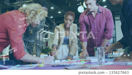 Brainstorming group of five professionals leaning over office table, using markers and sticky notes 135627663