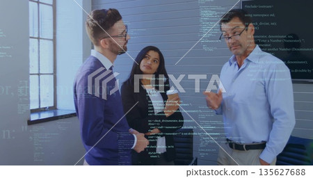Discussing project, three professionals standing by conference table in meeting room, coffee cup 135627688