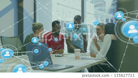 Collaborating professionals reviewing papers and laptops in meeting room, with network overlays 135627721