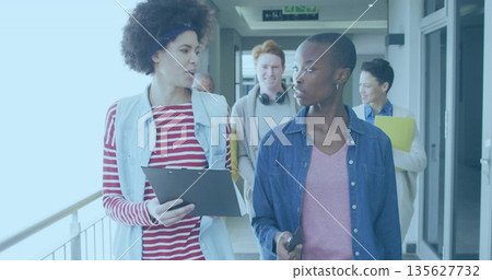 Walking two women leading peers along hallway, with clipboard smartphone headphones yellow folder 135627732