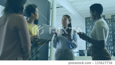 Standing business casual women holding laptops tablets smartphones at modern office with coffee cup 135627738