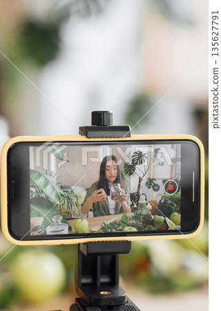 A young woman films herself preparing a healthy meal with fresh ingredients for her online audience 135627791