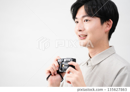 Young man holding a film camera Young man holding a film camera 135627863