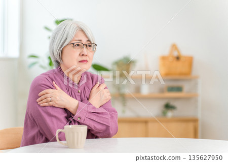 一位頭髮花白的老婦人在家裡的客廳和餐廳裡瑟瑟發抖(房屋,隔熱,隔熱性能,氣密性) 一位頭髮花白的老婦人在家裡的客廳和餐廳裡瑟瑟發抖(房屋,隔熱,隔熱性能,氣密性) 135627950