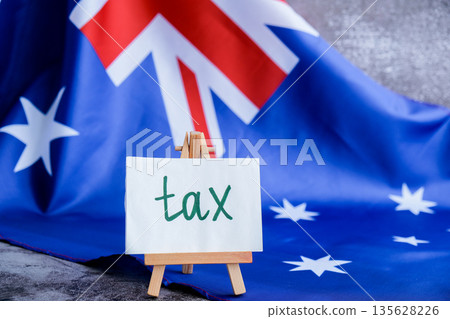 Message text TAX beside Australian flag for government or finance communication. National identity for tax awareness campaigns. Concept of revenue, legislation Message text TAX beside Australian flag for government or finance communication. National identity for tax awareness campaigns. Concept of revenue, legislation 135628226