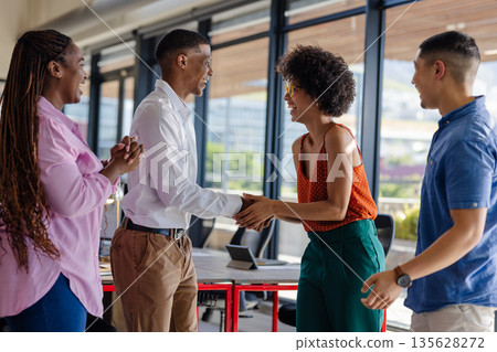 Greeting with handshake, colleagues smiling and connecting in modern office 135628272