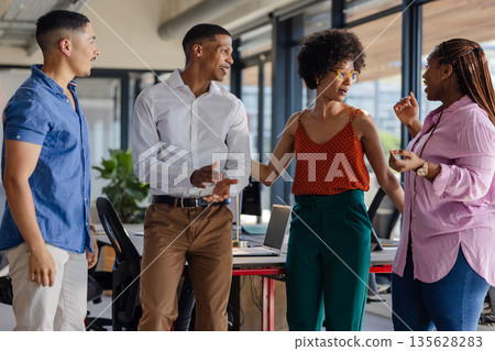 Colleagues in office discussing project, smiling and engaging in lively conversation Colleagues in office discussing project, smiling and engaging in lively conversation 135628283