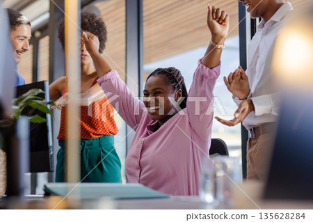 African American woman celebrating success with colleagues in modern office setting African American woman celebrating success with colleagues in modern office setting 135628284
