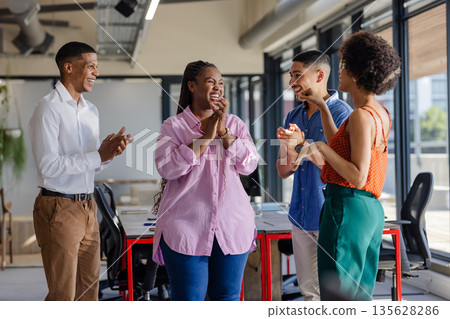 Colleagues in office clapping and smiling during successful team meeting 135628286