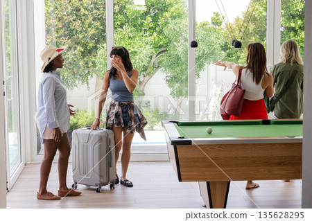 Women arriving at vacation home with luggage, exploring bright living room 135628295
