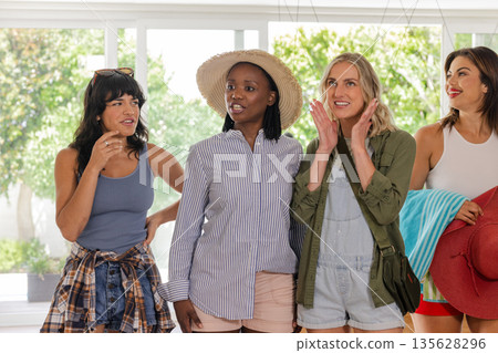 Group of diverse women enjoying conversation and laughter at home, feeling excited Group of diverse women enjoying conversation and laughter at home, feeling excited 135628296