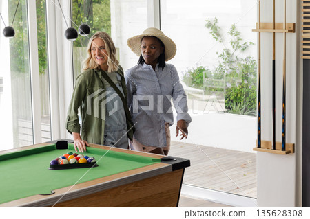 Two women enjoying leisure time by pool table in bright, modern room 135628308