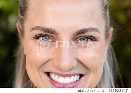 Smiling brightly outdoors, woman showing happiness in sunny park setting Smiling brightly outdoors, woman showing happiness in sunny park setting 135628347