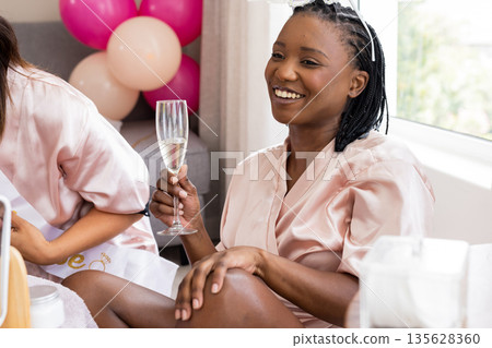 African American woman in silk robe enjoying champagne at home, smiling happily African American woman in silk robe enjoying champagne at home, smiling happily 135628360
