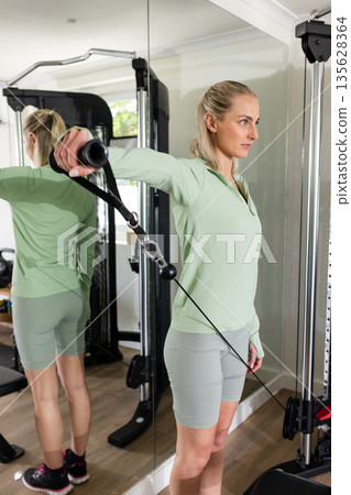 Woman exercising with cable machine in home gym, focusing on strength training 135628364