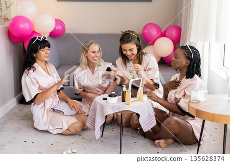 Women in silk robes enjoying makeup session and laughter during fun gathering Women in silk robes enjoying makeup session and laughter during fun gathering 135628374