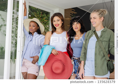 Diverse group of women smiling and enjoying vacation together at resort entrance 135628379