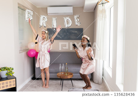 Celebrating bridal shower, joyful women in robes with balloons and decorations Celebrating bridal shower, joyful women in robes with balloons and decorations 135628436