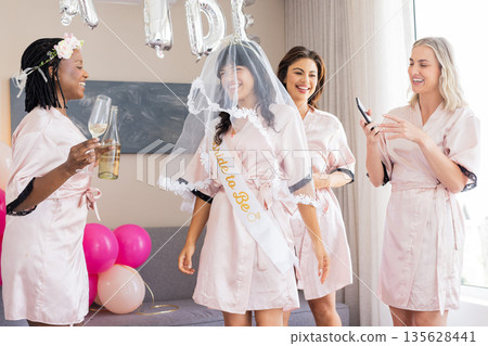 Women in matching robes celebrating bridal shower with champagne and balloons Women in matching robes celebrating bridal shower with champagne and balloons 135628441