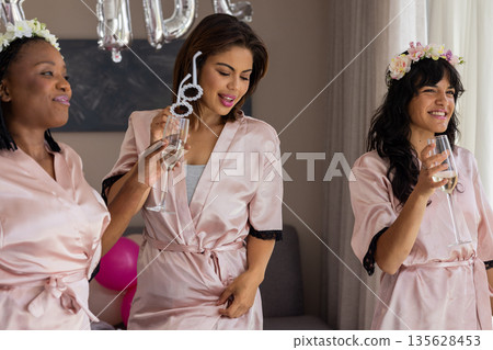 Women in robes celebrating with champagne and flower crowns at party Women in robes celebrating with champagne and flower crowns at party 135628453