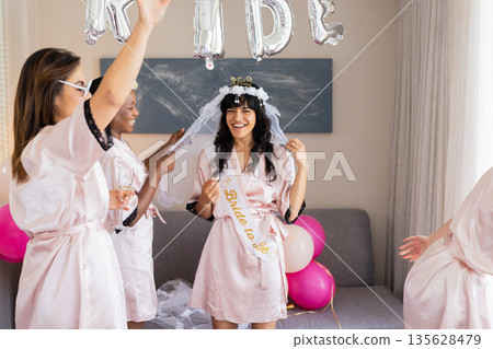 Celebrating bride-to-be, women in robes enjoying bachelorette party with balloons Celebrating bride-to-be, women in robes enjoying bachelorette party with balloons 135628479