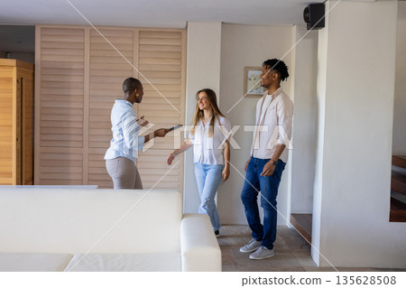 Real estate agent showing mixed friends around modern apartment, discussing features Real estate agent showing mixed friends around modern apartment, discussing features 135628508