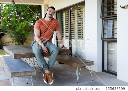 Man sitting on outdoor bench in casual attire, relaxing and enjoying day Man sitting on outdoor bench in casual attire, relaxing and enjoying day 135628509