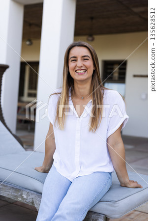Smiling woman sitting on bench outdoors, enjoying sunny day and relaxing Smiling woman sitting on bench outdoors, enjoying sunny day and relaxing 135628512