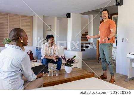 Friends enjoying conversation in modern living room, smiling and engaging warmly Friends enjoying conversation in modern living room, smiling and engaging warmly 135628526