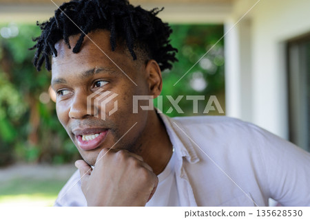 Smiling young man outdoors, looking thoughtful and enjoying sunny day Smiling young man outdoors, looking thoughtful and enjoying sunny day 135628530