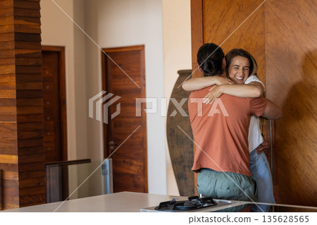 Friends embracing warmly in modern home, sharing joyful moment together 135628565