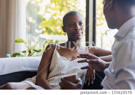 Friends talking and relaxing on sofa at home, enjoying casual conversation Friends talking and relaxing on sofa at home, enjoying casual conversation 135628579