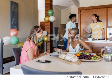 Friends enjoying conversation and snacks at home during casual gathering 135628582