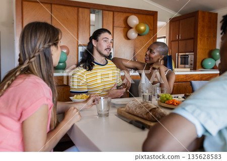 Friends enjoying conversation and snacks at home, sharing laughter and stories Friends enjoying conversation and snacks at home, sharing laughter and stories 135628583