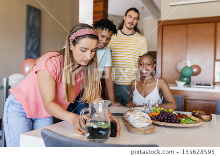 Friends gathering at home, enjoying snacks and drinks around dining table 135628595