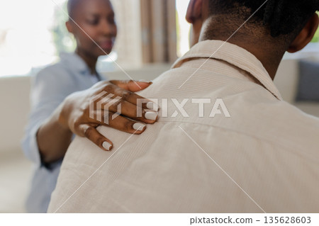Offering support, African American woman gently comforting friend at home 135628603