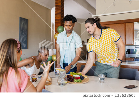 Sharing fresh fruit platter, friends laughing and talking together at home Sharing fresh fruit platter, friends laughing and talking together at home 135628605