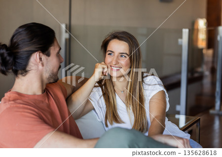 Smiling friends relaxing on sofa, enjoying conversation in cozy living room Smiling friends relaxing on sofa, enjoying conversation in cozy living room 135628618