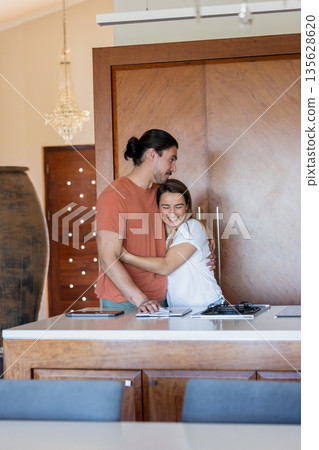 Couple embracing in modern kitchen, smiling and enjoying quality time together Couple embracing in modern kitchen, smiling and enjoying quality time together 135628620