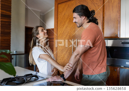 Couple laughing and enjoying conversation in modern kitchen at home 135628658