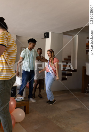 Celebrating graduation, friends dancing joyfully with balloons and decorations indoors 135628664