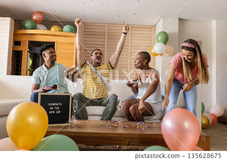 Celebrating new job, friends cheering with balloons and confetti in living room Celebrating new job, friends cheering with balloons and confetti in living room 135628675