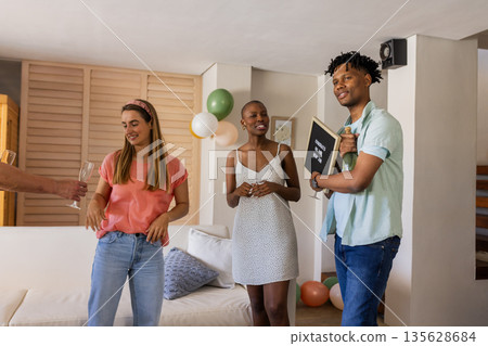 Friends celebrating at home, holding champagne glasses and enjoying conversation Friends celebrating at home, holding champagne glasses and enjoying conversation 135628684