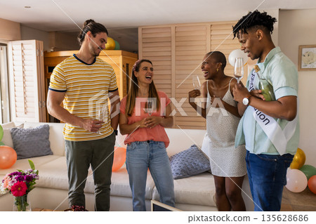 Graduation celebration, diverse friends holding champagne glasses and laughing at home Graduation celebration, diverse friends holding champagne glasses and laughing at home 135628686