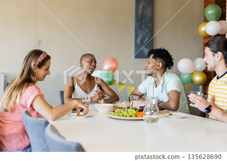 Friends enjoying conversation and snacks at home, sharing laughter and stories Friends enjoying conversation and snacks at home, sharing laughter and stories 135628690