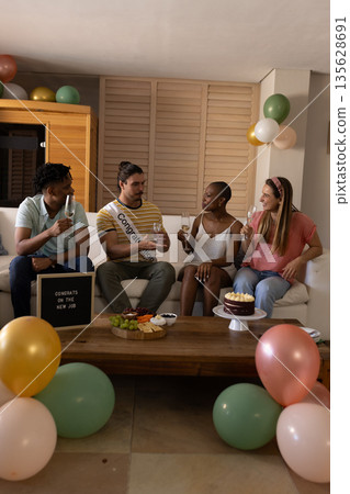 Celebrating new job, diverse friends enjoying drinks and cake at home party 135628691