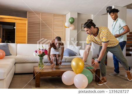 Decorating living room with balloons and flowers, friends smiling for celebration 135628727