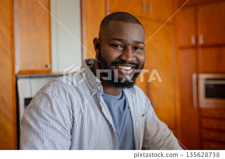 Smiling man in kitchen wearing casual shirt, enjoying relaxed moment at home Smiling man in kitchen wearing casual shirt, enjoying relaxed moment at home 135628738